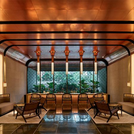 The Ruma Hotel And Residences Kuala Lumpur Exterior photo The image shows a stylish interior space with a modern and elegant design. The walls have a sleek, warm-toned finish, and there are large windows that provide natural light. The ceiling features striking architectural lines, likely in a metallic mate