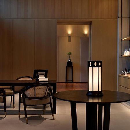 The Ruma Hotel And Residences Kuala Lumpur Exterior photo The photo shows a modern, minimalist interior space. It features a wooden wall with soft lighting, enhancing a calm atmosphere. In the foreground, there is a round table with a uniquely designed lamp on it. Surrounding the table, there are stylish wo