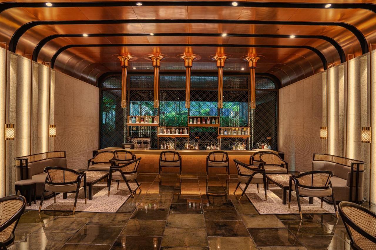 The Ruma Hotel And Residences Kuala Lumpur Exterior photo The photo shows a stylish interior of a bar or lounge area. The space features a combination of elegant materials, including polished metal accents and warm lighting. A wooden bar counter is centrally located, with several shelves displaying various 